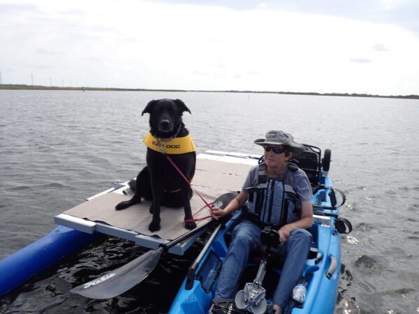 A person and a dog on a boat with a one-side outrigger